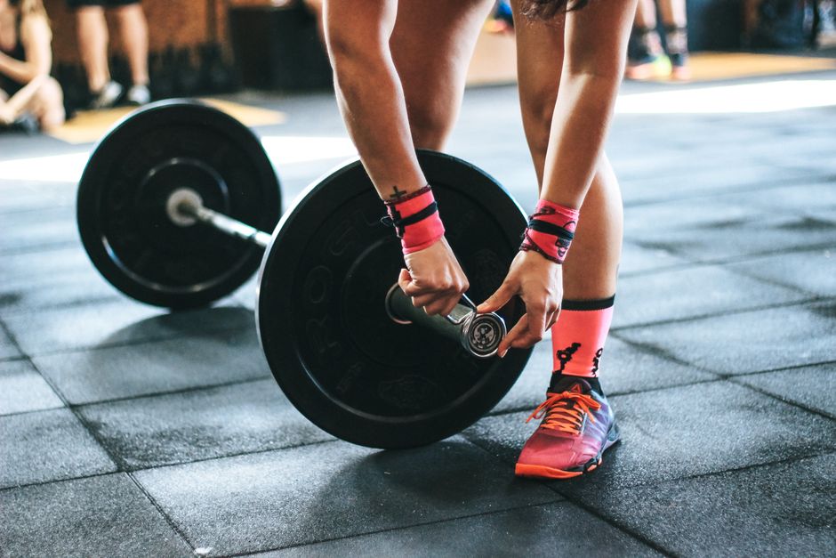 Athlete tightening barbell plates in a gym, emphasizing fitness i snagu